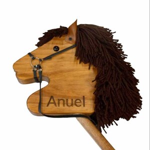 May include: A wooden toy horse with a brown mane and tail, a black bridle, and the name "Anuel" engraved on the side.