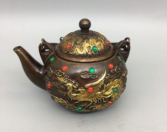 Tetera antigua de cobre dorado con diseño de dragón y fénix, decoración chinoiserie con incrustaciones de gemas y asa de transporte.