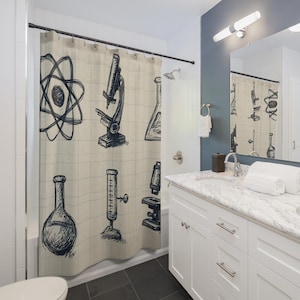 May include: A beige shower curtain featuring a scientific theme with hand-drawn illustrations. The design includes an atom model, microscopes, beakers, and graduated cylinders. The artwork is in black ink, creating a classic, educational aesthetic for a bathroom.