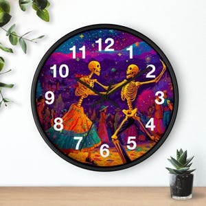 May include: Round black wall clock featuring a vibrant Day of the Dead design. Two dancing skeletons are the focal point, set against a colorful background of a festive scene. The clock face has white numerals.
