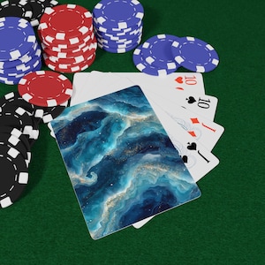 May include: Poker set on a green felt surface. The set includes stacks of red, blue, and black poker chips, along with playing cards featuring a blue and gold abstract design. The cards show the number 10.