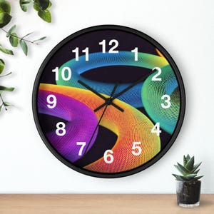 May include: A round wall clock with a black frame and a black face featuring a vibrant, abstract design of swirling, multi-colored lines in shades of purple, orange, yellow, and green. The clock has white numerals and thin black hour, minute, and second hands.
