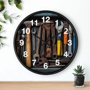 May include: A round wall clock with a black frame. The clock face features a collection of vintage tools, including wrenches, pliers, and a hammer, arranged against a blue background. White numerals mark the hours.
