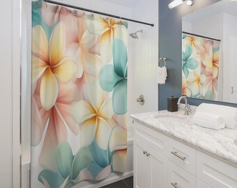 May include: A floral shower curtain featuring large, watercolor-style plumeria flowers in shades of peach, yellow, and teal. The curtain hangs in a bathroom with white cabinetry and a marble countertop.
