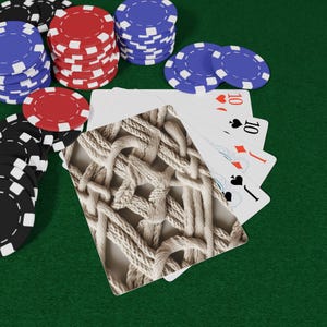 May include: A poker game scene with playing cards showing the number ten, and stacks of red, blue, and black poker chips on a green felt surface. A card with a beige woven pattern is in the foreground.