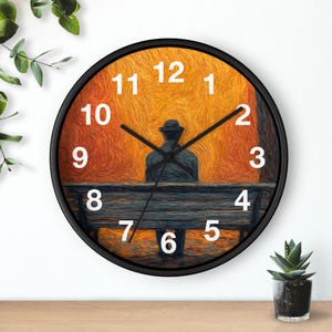 May include: Black-framed wall clock featuring a painting of a person sitting on a bench, with an orange and yellow background. White numerals mark the hours. Black clock hands indicate the time.