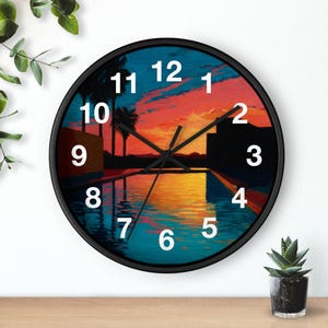 May include: A round wall clock with a black frame. The clock face features a vibrant sunset scene over a pool with palm trees. White numerals mark the hours. The clock hands are black.