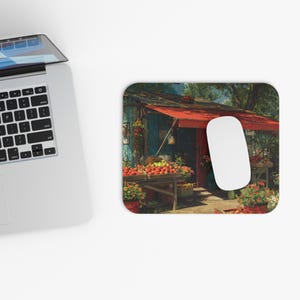 May include: Mousepad featuring a vibrant illustration of a fruit stand with a red awning and a variety of produce. The scene includes wooden tables laden with red and yellow fruits, surrounded by potted flowers, creating a colorful and inviting display.