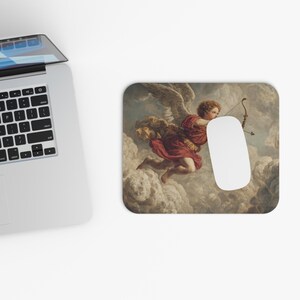 May include: A rectangular mousepad featuring a classical painting of a cherub with wings, holding a bow and arrow. The cherub is dressed in red robes, set against a cloudy background. A white computer mouse rests on the pad.
