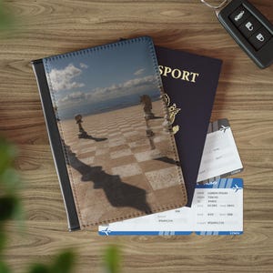 Peut inclure: Un porte-passeport avec un motif de jeu d'échecs surréaliste, un passeport bleu foncé et deux billets d'avion. Le porte-passeport présente un paysage de pièces d'échecs. Une clé de voiture est également visible.