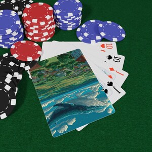 以下が含まれることがあります： ポーカーゲームのシーン。トランプとポーカーチップがあります。カードには空にクジラが描かれています。赤、青、黒、白のポーカーチップの山が、緑色のフェルトの表面にあるカードの周りに散らばっています。