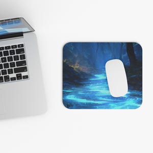 May include: A rectangular mousepad featuring a vibrant blue and green forest scene with a glowing river. A white computer mouse rests on the pad. The scene evokes a sense of fantasy and nature.