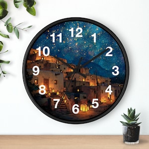 Puede incluir: Reloj de pared redondo con marco negro. La esfera del reloj presenta una escena nocturna de un pueblo con edificios iluminados bajo un cielo estrellado. Números blancos marcan las horas.