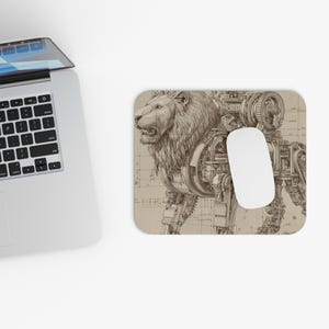 Op de afbeelding: Een beige muismat met een gedetailleerde illustratie van een leeuw met mechanische componenten. De kop en manen van de leeuw zijn ingewikkeld getekend, met tandwielen en machines die zijn lichaam vormen. Een witte computermuis ligt op de mat.