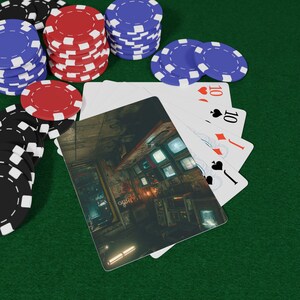 Puede incluir: Una colección de fichas de póquer rojas, azules y negras dispuestas en pilas y esparcidas junto a una mano de cartas. Una carta presenta una escena interior detallada, oscura y atmosférica con múltiples monitores brillantes.