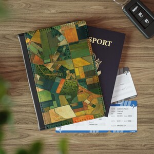 May include: A passport cover with a patchwork design in green, yellow, and orange, a dark blue passport, and two airline tickets on a wooden surface. The passport cover has a landscape pattern. The passport reads 'SPORT'.