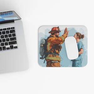 May include: A rectangular mousepad featuring an illustration of a firefighter and a medical professional giving each other a high five. The firefighter is wearing an orange uniform and helmet. The medical professional is wearing blue scrubs. A white computer mouse is on the mousepad.