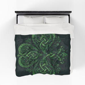 May include: A green shamrock design on a dark background, displayed on a bed. The shamrock features intricate Celtic knot patterns. The bedding includes a black bed frame and white pillows and sheets. The shamrock is a symbol of luck and Irish heritage.