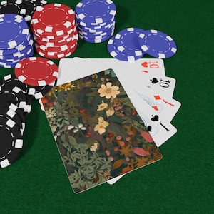 Puede incluir: Una taza de cerámica blanca con asa negra y el texto "But First, Coffee" en negrita negra. La taza se encuentra sobre un fondo borroso, sugiriendo un ambiente acogedor.