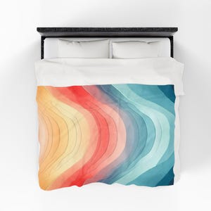 May include: A bed with a black frame, white pillows, and a duvet cover. The duvet features a colorful, abstract design with curved lines in shades of orange, red, yellow, and blue, creating a layered effect.
