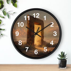 May include: A round wall clock with a black frame and white numerals. The clock face features a desert landscape illustration with a large, ancient stone archway glowing with golden light in the centre, and black hour, minute, and second hands.