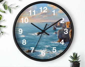May include: A round wall clock with a black frame. The clock face features a seascape painting with blue water, cliffs, and a sky with clouds. The clock hands are black, and the numbers are white.