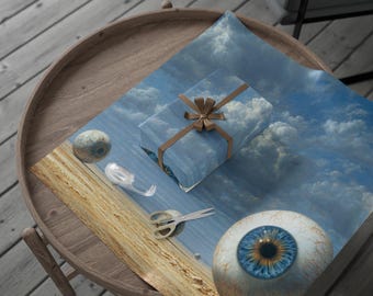 May include: A surreal still life featuring a wrapped gift with a brown ribbon, scissors, and a large eyeball. The wrapping paper has a blue sky and cloud design. A small, round object and a clear plastic object are also present.