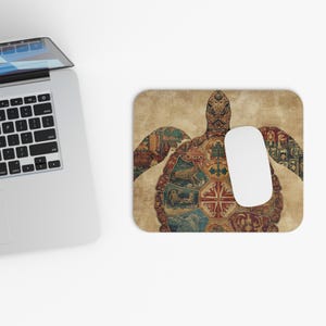 May include: A beige mousepad with a detailed turtle design. The turtle's shell is filled with various illustrations in shades of red, brown, and blue. A white computer mouse rests on the right side of the mousepad.