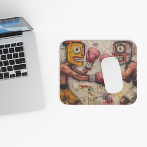 Könnte beinhalten: Mauspad mit einem abstrakten Gemälde von zwei Boxern mit gelben und roten Gesichtern, die rosa Boxhandschuhe tragen. Das Kunstwerk hat einen strukturierten, Vintage-Look. Eine weiße Computermaus liegt auf dem Pad, neben einem Laptop.