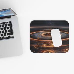 Könnte beinhalten: Ein rechteckiges Mauspad mit einem wirbelnden Galaxiemuster in Orange-, Gold- und Schwarztönen. Eine weiße Computermaus liegt auf dem Pad, neben einem Laptop.