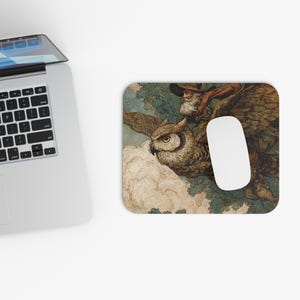 May include: A rectangular mousepad featuring a vintage illustration of a large owl in flight, carrying a person. The owl is brown and tan, with a detailed depiction of feathers. The person is wearing a hat and has a long white beard. A white mouse is on the mousepad.