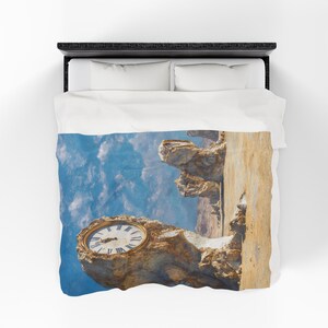 May include: A duvet cover featuring a surreal image of a clock embedded in a rock formation against a blue sky. The clock has a gold frame and black Roman numerals. The overall theme is time and nature.