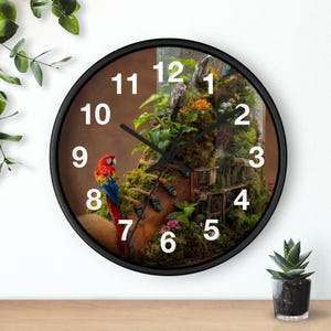 May include: A round wall clock with a black frame and white numbers. The clock face features a graphic of a brown boot covered in green moss and small plants, with a vibrant red, yellow, and blue macaw parrot perched on the side of the boot.