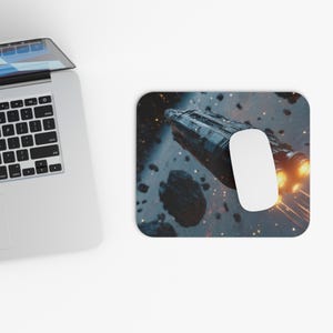May include: A computer mouse and mousepad featuring a space scene with a spaceship and asteroids. The mousepad has a black background with a spaceship design and a white computer mouse.