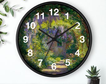Könnte beinhalten: Runde Wanduhr mit schwarzem Rahmen, die ein impressionistisches Gartenbild zeigt. Weiße Ziffern markieren die Stunden, mit schwarzen Zeigern. Eine kleine Topfpflanze ist sichtbar. Der Durchmesser der Uhr beträgt ca. 30 cm.