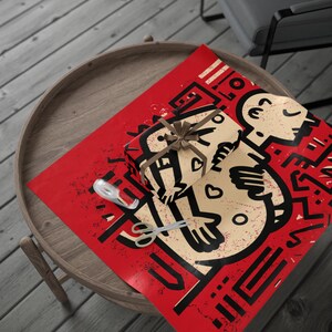 Puede incluir: Una caja de regalo envuelta con una cinta marrón se encuentra sobre una hoja de papel de regalo rojo. El papel de regalo presenta un diseño gráfico en negro y beige. También hay tijeras y cinta adhesiva en el papel.