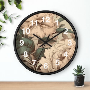 May include: A round wall clock with a black frame and a beige face featuring a detailed illustration of large, light-colored flowers and dark green leaves. The clock has white numbers from 1 to 12 and thin black hour, minute, and second hands.