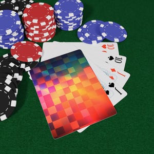May include: A deck of playing cards with a vibrant, multi-coloured pixelated gradient back design, fanned out to reveal a ten of hearts, ten of spades, jack of diamonds, and jack of spades, surrounded by stacks of red, blue, and black poker chips.