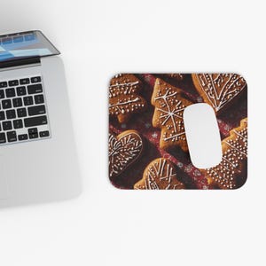 May include: A computer mouse and mousepad with a festive design. The mousepad displays gingerbread cookies in tree and heart shapes, decorated with white icing, set against a red background with a snowflake pattern.