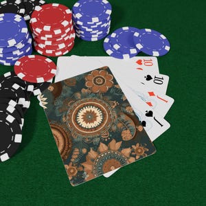 May include: Poker set with playing cards and poker chips. The cards have a floral design on the back and show the ten of hearts, spades, diamonds, and clubs. Stacks of red, blue, and black poker chips are visible on a green surface.