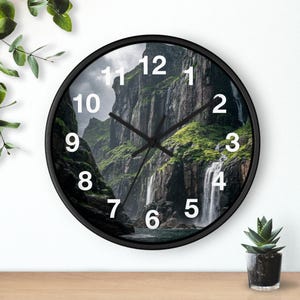 May include: A round wall clock with a black frame. The clock face features a scenic landscape of a waterfall cascading down a rocky cliff, with white numerals marking the hours.