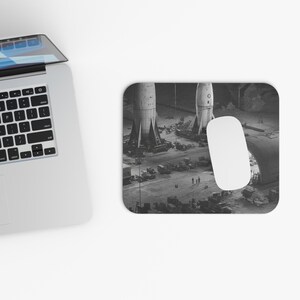 May include: Black and white mousepad featuring a vintage photograph of two rockets on a launch pad. The image includes a white computer mouse and a laptop.