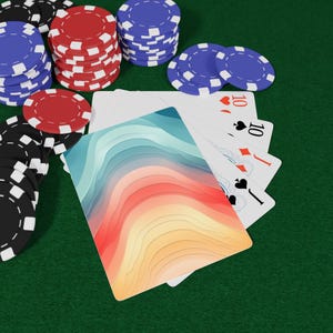 May include: A selection of poker chips in black, red, and blue are arranged on a green felt surface. Playing cards showing the number 10 are visible, alongside a card with a layered design in blue, orange, and yellow.