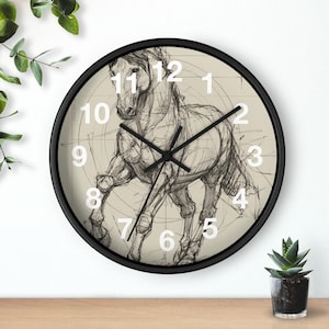 May include: A black-framed wall clock featuring a sketch of a running horse. The clock face is a light beige color with a detailed pencil drawing of a horse. White numerals mark the hours.
