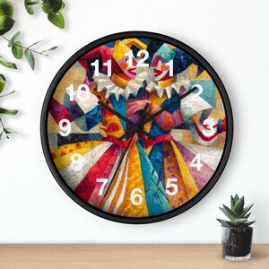 May include: Round wall clock with a black frame featuring a colorful abstract design of a harlequin figure. The clock face displays white numerals against the vibrant artwork, with hands indicating the time. The design incorporates a variety of colors.