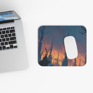 Pode incluir: Um mousepad retangular com uma paisagem de fantasia com altas e escuras torres contra um céu laranja e azul. Um mouse de computador branco repousa sobre o mousepad, ao lado de um laptop.