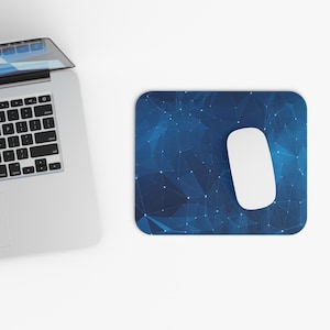 May include: A white computer mouse rests on a blue mousepad with a geometric pattern of interconnected lines and dots. A laptop is partially visible in the upper left corner, suggesting a workspace setup.