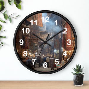 Könnte beinhalten: Eine runde Wanduhr mit schwarzem Rahmen und einem Fotodruck eines belebten Außenmarktes mit Menschen und hängenden Textilien. Das Zifferblatt zeigt große weiße Ziffern von 1 bis 12 sowie schwarze Stunden-, Minuten- und Sekundenzeiger.
