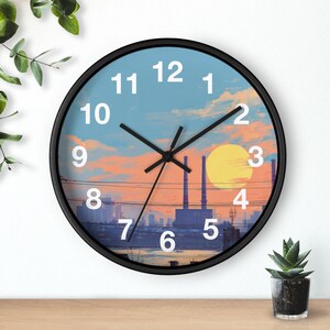 May include: A round wall clock with a black frame. The clock face features a cityscape scene with a sunset, a large yellow sun, and the numbers 1 through 12. The clock hands are black.