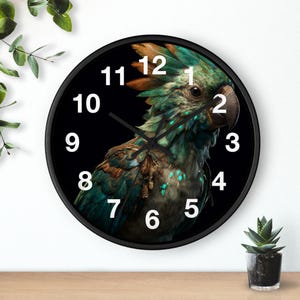 Puede incluir: Un reloj de pared redondo con marco negro y esfera negra que muestra una ilustración detallada de un loro con plumas de color verde azulado, marrón y naranja. El reloj tiene números arábigos blancos del 1 al 12 y manecillas negras finas.